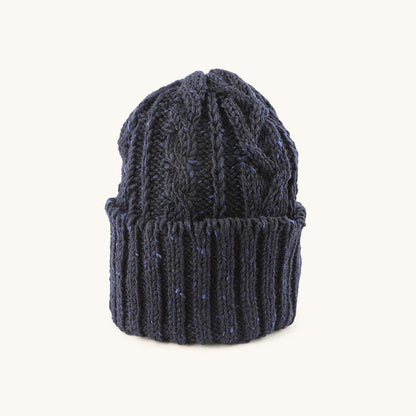Dark navy blue cable knit cap with lighter blue flecks, featuring prominent cable patterns and a ribbed cuff.