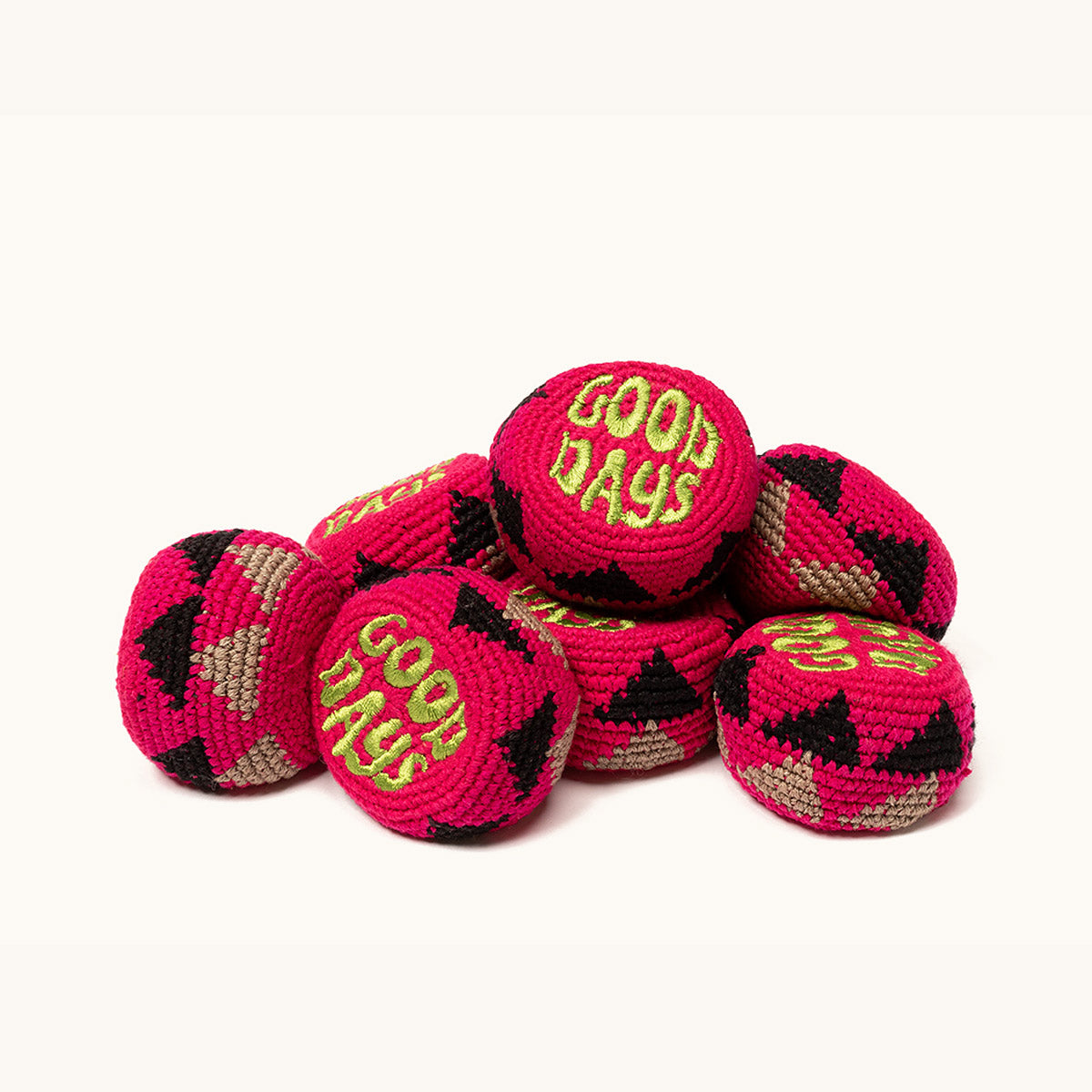 Fuchsia footbags by Good Days with green embroidered text and black and tan triangular patterns, piled together.