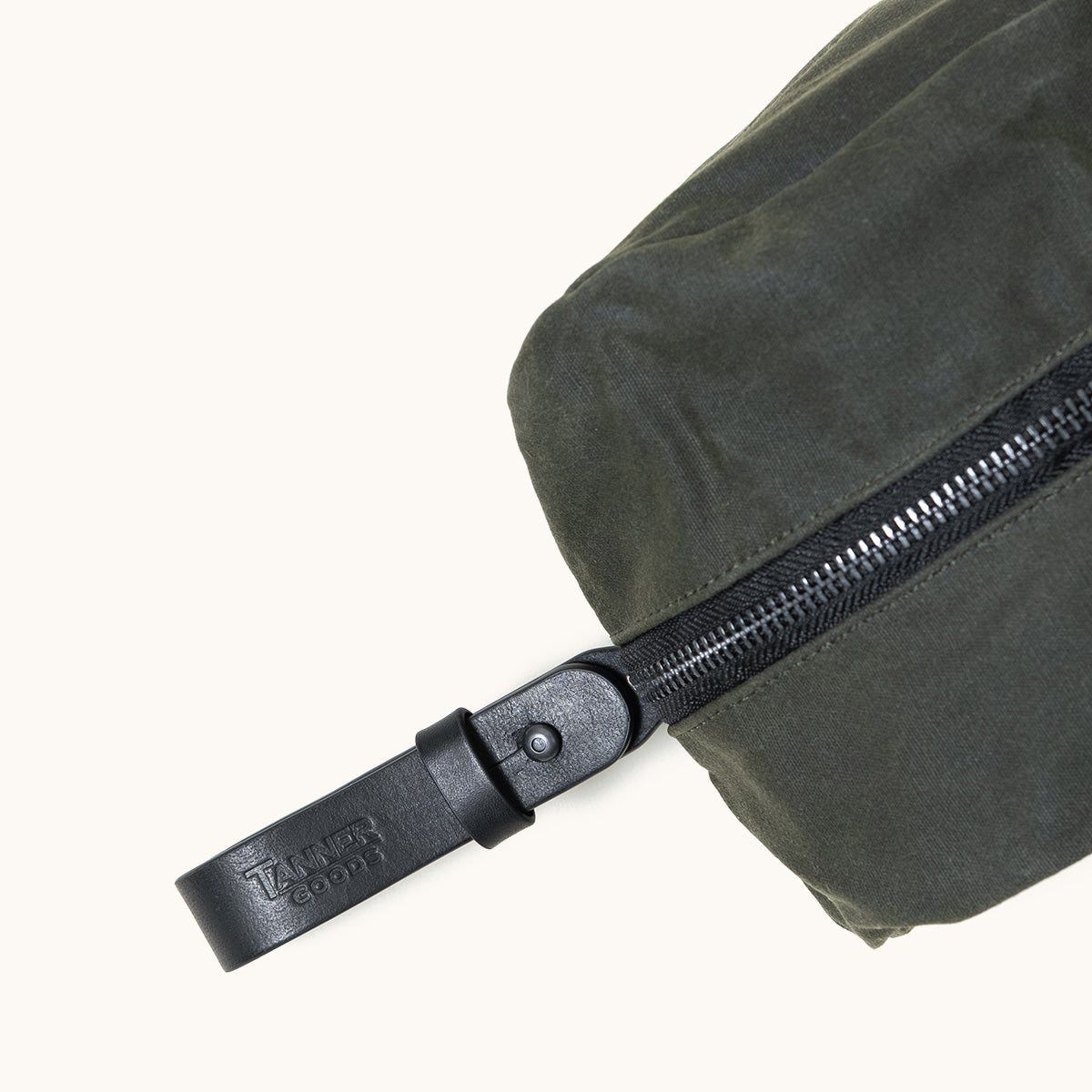 Juniper green waxed canvas Dopp kit by Tanner Goods, featuring a black zipper and leather pull tag.