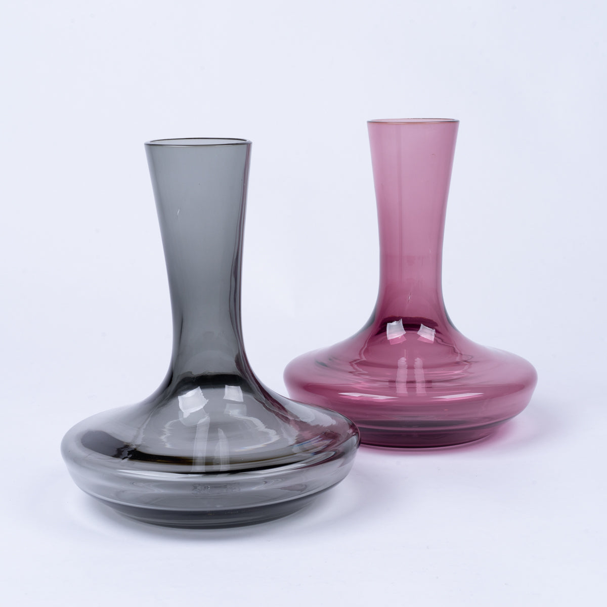 Two B Grade Decanters, one grey and one purple glass, featuring slender necks and wide, round bases.