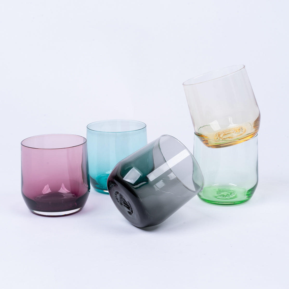 Colorful B grade cocktail glasses, some stacked, some scattered, against a white background.