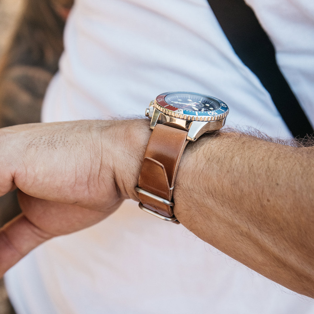 Cordovan leather NATO watch strap in natural tone, worn on wrist with silver buckle, paired with dive watch, side view