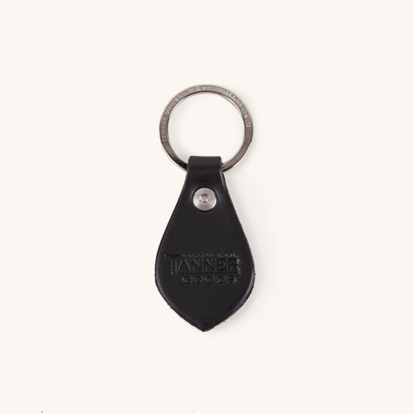 Black leather key fob with a silver keyring, a metal rivet, and embossed 'TANNER GOODS' text.