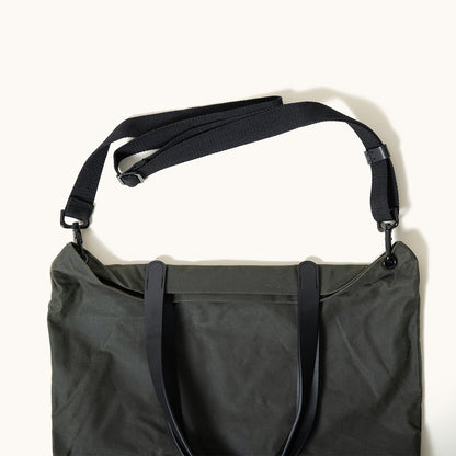 Juniper Green waxed canvas Simple Tote with black leather carry handles and an adjustable black shoulder strap, seen from above.