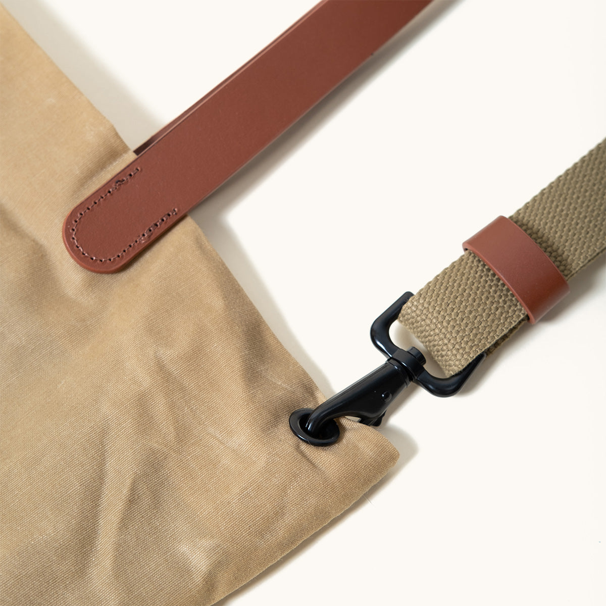 Close-up of a Utility Tan Waxed Canvas Simple Tote with brown leather accents and an olive green strap with a black metal hook.