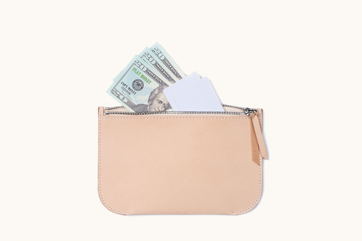 Natural leather universal zip pouch with a zipper, holding play money and white cards.