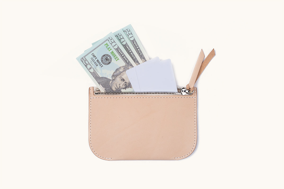 Light tan leather universal zip pouch open, revealing play money and white cards inside.