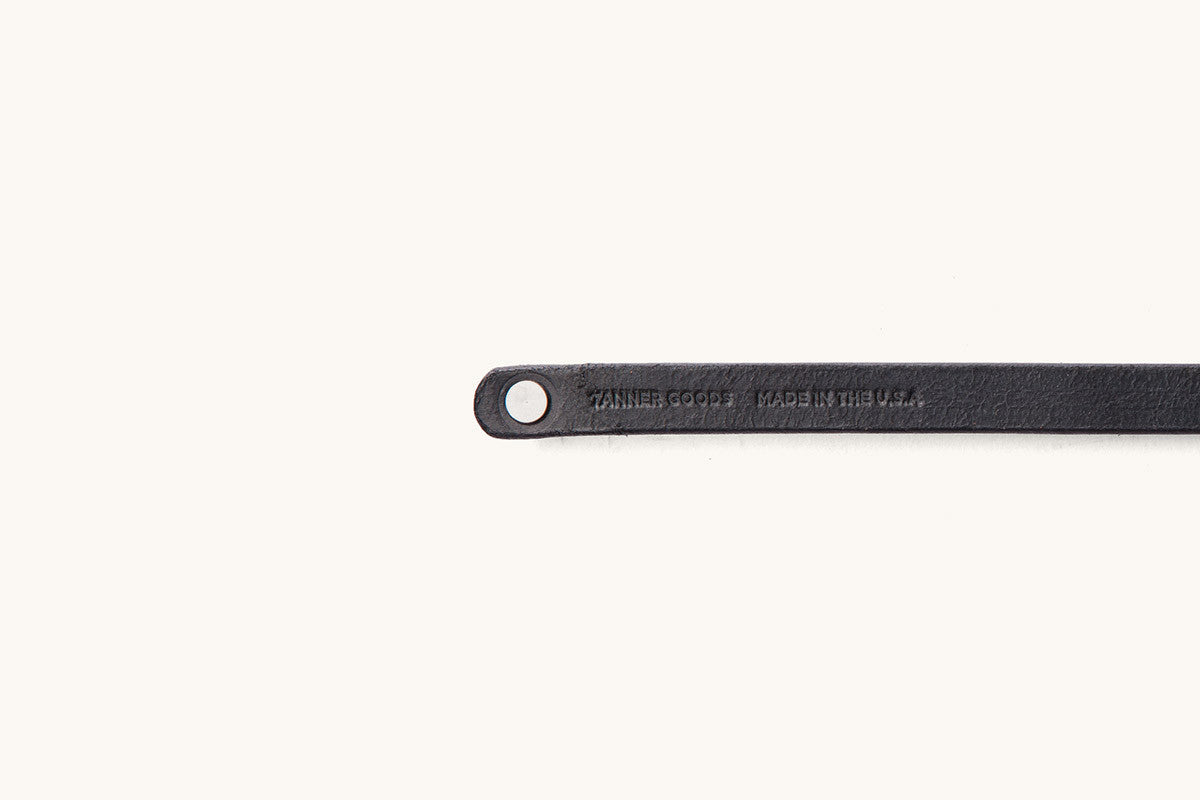 Cropped black leather double wrap wristband by Tanner Goods, featuring a metal snap and text 'TANNER GOODS MADE IN THE U.S.A.' stamped.