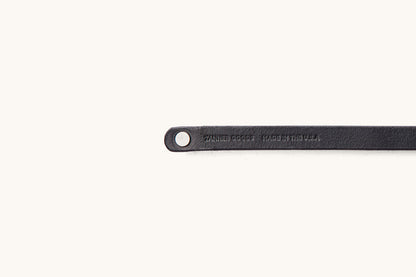 Cropped black leather double wrap wristband by Tanner Goods, featuring a metal snap and text 'TANNER GOODS MADE IN THE U.S.A.' stamped.