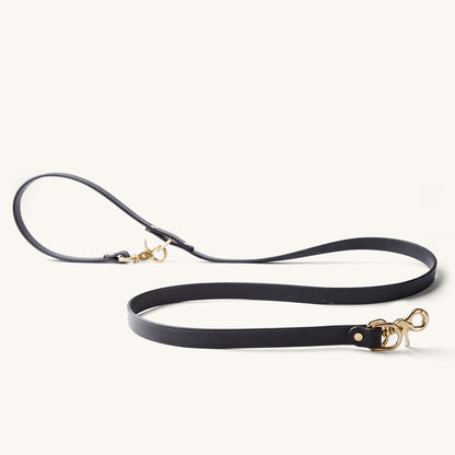 Black convertible canine lead with brass-tone clasps, arranged on a light background.