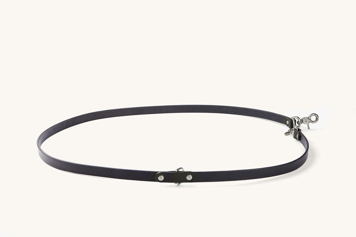 Black convertible canine lead with silver-tone metal hardware, featuring rivets and a swivel snap hook, arranged in an oval.