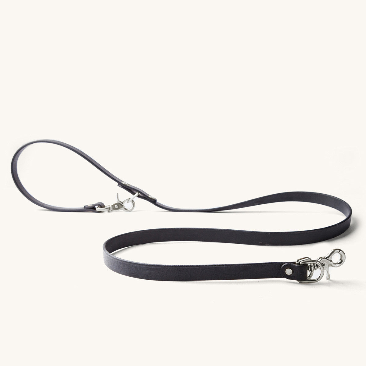 Black convertible canine lead with silver-tone snap hooks, made of a flat strap, displayed on white.