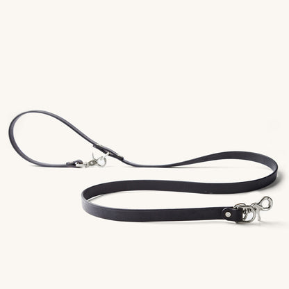 Black convertible canine lead with silver-tone snap hooks, made of a flat strap, displayed on white.