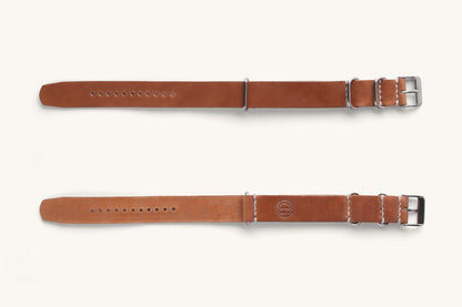 Cordovan leather NATO watch strap in natural brown, featuring silver-tone hardware and white stitching, shown flat with embossed logo on one side