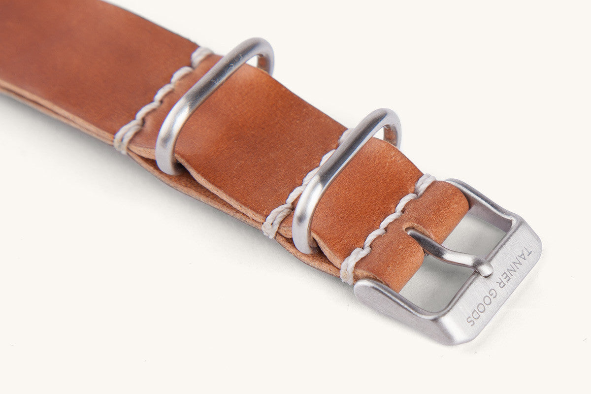 Cordovan leather NATO watch strap in natural brown, by Tanner Goods, with silver-toned hardware and white stitching, close-up side view