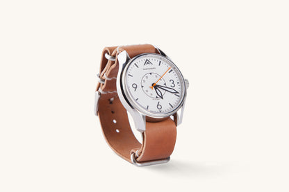 Cordovan leather NATO watch strap in natural tan, featuring silver hardware and a minimalist design, shown on a white-dial watch in side view.