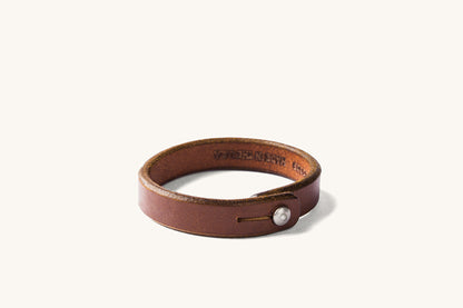 Brown leather wristband with metal rivet closure.