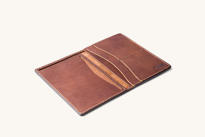 Cognac leather travel wallet by Tanner Goods, open to reveal multiple card slots and contrasting stitching on a white background.