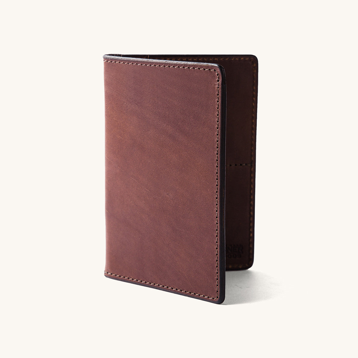 Cognac leather travel wallet, standing upright and slightly open, revealing fine stitching and a minimalist design.