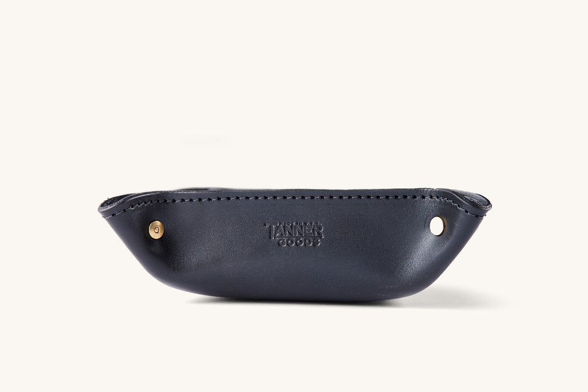 Black leather valet tray from Tanner Goods with gold-toned snaps at the corners and an embossed logo inside.